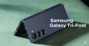 Samsung Galaxy Tri-Fold smartphone partially unfolded in tent mode on green surface showing triple-camera array and dual hinges